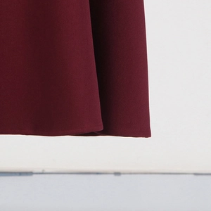 Detailed view of the burgundy fabric hem with smooth stitching on a slim fit top