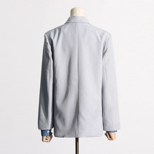 Detail of light gray blazer back showing denim patchwork cuffs and silver metal button