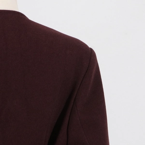 Macro detail of wine red wool coat showing shoulder seam stitching and soft fabric texture