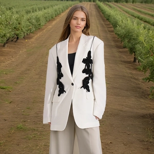 Detail of white blazer featuring symmetrical black butterfly embroidery and silk threads