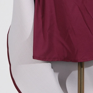Close-up of burgundy twill fabric showing fine texture and stitching on a mannequin