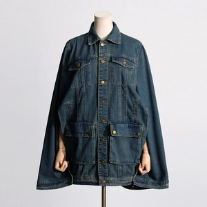 Detail of dark blue denim cape jacket with metal buttons and large flap pockets