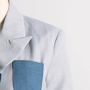 Detail of light grey blazer with contrast navy pocket and fine twill texture
