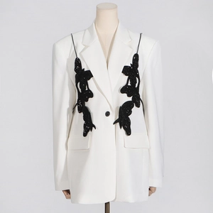 Detail of 3D black butterfly appliques on a classic white peak lapel blazer jacket