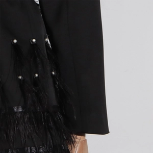 Dettaglio dell'abito blazer nero con eleganti piume di struzzo e decorazioni di perle
