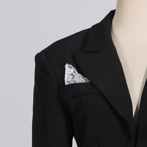 Detailed view of black blazer bodysuit with white lace ruffle insert on the chest pocket