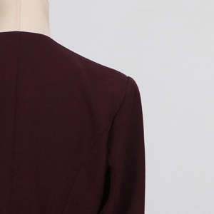 Detail of burgundy blazer shoulder showing textured fabric and precise stitching