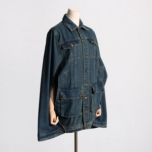 Detail view of dark blue denim cape jacket showing metal buttons and flap pockets