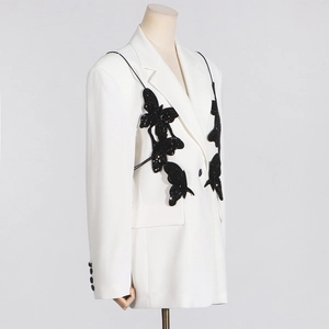 Detailed view of 3D black butterfly appliques on white double-breasted blazer