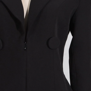 Detailed close-up of matte black fabric texture and matching decorative buttons on the suit