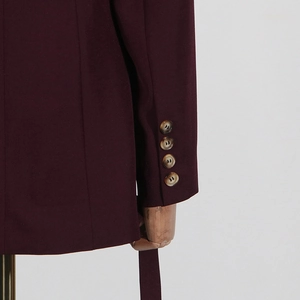 Close-up of wine red blazer sleeve with four brown tortoiseshell buttons and woven texture