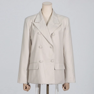Detail of beige double-breasted blazer featuring peak lapels and decorative flap pockets