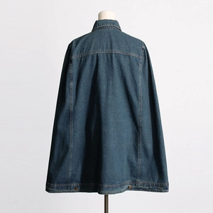 Detail of the back of a dark blue denim cape with contrast stitching and metal buttons