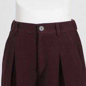 Detailed macro view of burgundy wool-textured trousers with pleated waist and black button