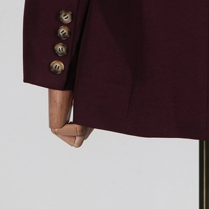 Detail view of wine red blazer sleeve with four marble-textured decorative buttons