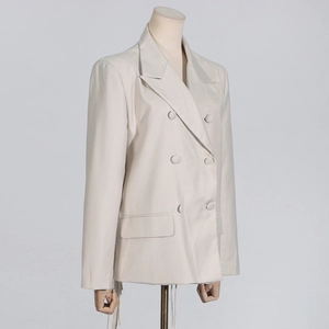 Close-up of double-breasted beige blazer with notched lapels and flap pockets