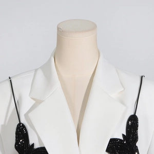 Close-up of white blazer with embroidered black butterfly detail and sequined texture