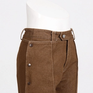 Close-up of brown trousers with white contrast stitching and side button details