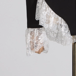 Detail of layered white lace ruffles and embroidery on black chic bodysuit sleeve