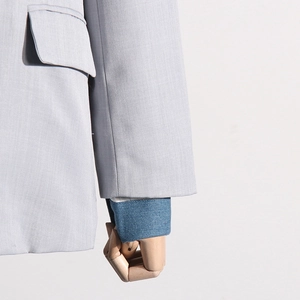Detail of light gray blazer showing pocket flap and denim cuff contrast sleeve texture