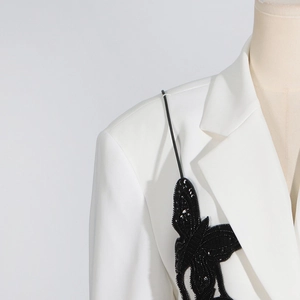 Detail of black sequined butterfly embroidery on a premium white blazer lapel