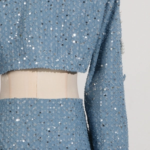 Detail of light blue denim with silver sequins and white pearl trim on the sleeve cuff