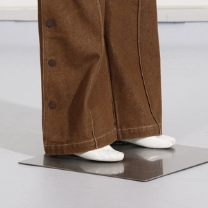 Detail of dark brown wide-leg cargo pants with side snap buttons and white contrast stitching