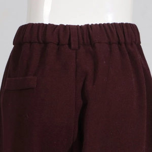 Detail of burgundy wide-leg trousers showing elastic waistband and wool-like fabric texture