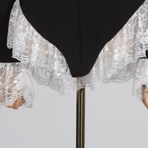 Detail of elegant black blazer bodysuit with white lace ruffles on sleeves and hemline