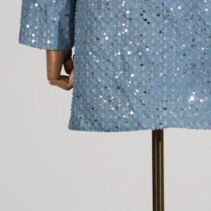 Detailed macro shot of light blue denim fabric with silver sequins and frayed hem