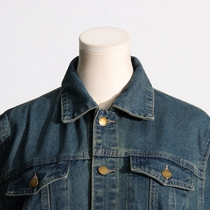 Detailed view of dark blue denim jacket collar and brass buttons with engraved texture