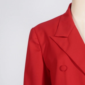 Detail of red structured blazer with peaked lapels and shoulder pads on a mannequin
