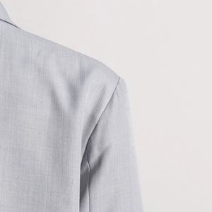 Detailed close-up of light blue blazer shoulder stitching and twill fabric texture