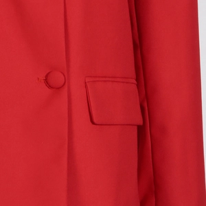 Detail shot of a red blazer featuring a fabric-covered button and a flap pocket design