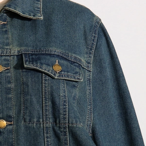 Detail of dark blue denim jacket showing collar, stitching and golden heritage buttons