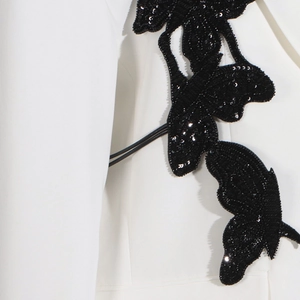 Detail of a white blazer featuring a large black sequined butterfly applique embroidery