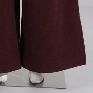 Detail of dark burgundy wide-leg trousers showing heavy fabric and fine stitching