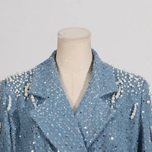 Detail of light blue denim jacket featuring silver sequins and white pearl embellishments