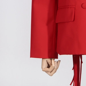 Detail of red blazer with flap pocket and decorative tassels on woven fabric
