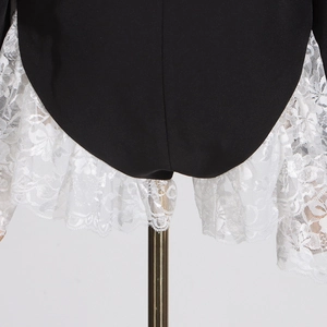 Detail of black fabric hem with ruffled white lace floral embroidery on the garment