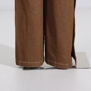 Detail of brown trousers featuring white contrast stitching and a stylish side slit design