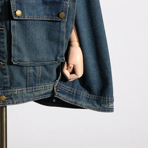 Detailed macro view of heavy denim jacket with metal logo buttons and flap pocket texture