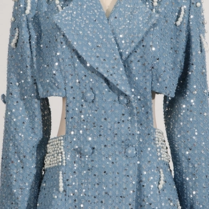 Detailed close-up of light blue sequined dress with white pearl trim and waist cut-outs