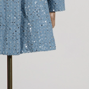 Detail of light blue denim dress with silver sequins and distressed fringe texture