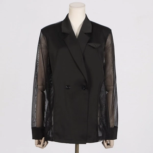 Détail d'un blazer noir avec manches en mesh transparent et boutons à double boutonnage