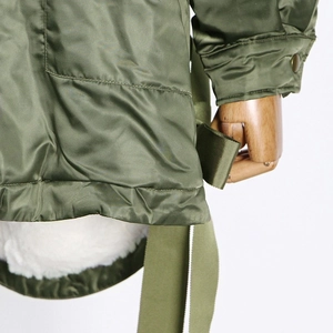 Detail of olive green parka coat with plush white lining and adjustable buttoned cuffs