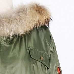 Detail of army green parka jacket featuring a fluffy faux fur collar and metal eyelets