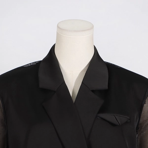 Détail de blazer noir élégant avec manches en tulle transparent et poche poitrine stylée