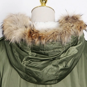 Detail view of the plush faux fur collar and hood on a military green parka jacket