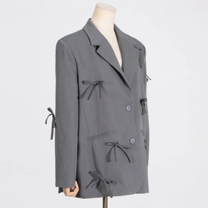 Vue détaillée du blazer gris avec nœuds papillon 3D et revers élégant chic